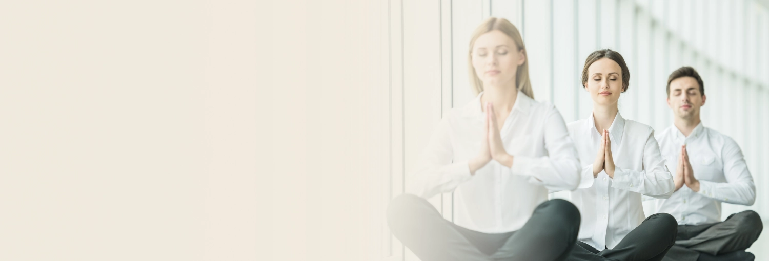Group of professionals in white attire practicing meditation in office setting