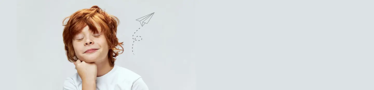 Рыжеволосый ребенок опирается подбородком на руку, что отражает интуитивную мысль и принятие решений.