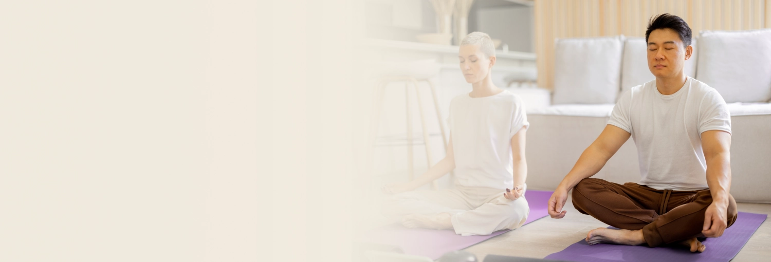 Woman in grey tank top meditating by a waterfall 