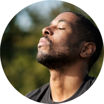A smiling male with both his palms facing downwards performing breathing exercise