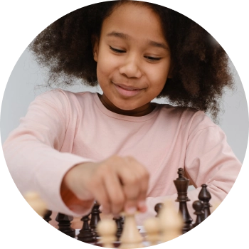 Young boy in blue shirt playing chess, focused on developing strategic thinking skills.