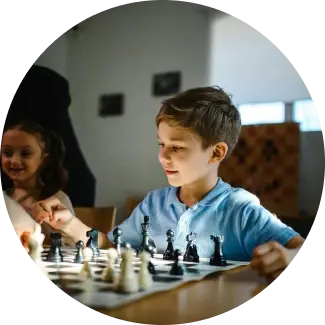 Junge im blauen Shirt spielt Schach, konzentriert auf die Entwicklung strategischer Denkfähigkeiten.
