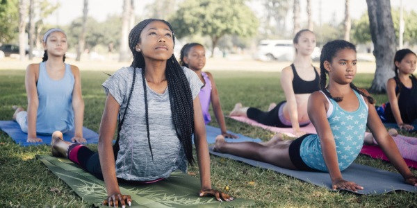 Un gruppo eterogeneo di partecipanti al programma YES! pratica tecniche di yoga durante il corso di leadership