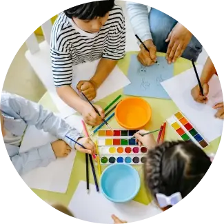 Bambini che disegnano e dipingono a un tavolo, rappresentando le abilità di vita ART Excel di The Art of Living.