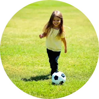 Ragazza in top giallo che gioca a calcio su un campo erboso, divertendosi con un gioco attivo.