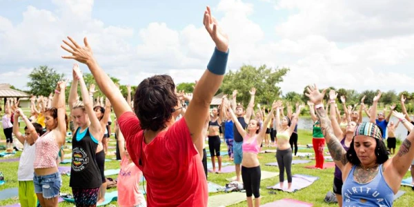 Un gruppo entusiasta di volontari di Art of Living alza le mani in segno di unione durante l'evento di servizio alla comunità all'aperto