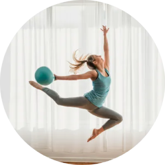 Woman leaping with a blue exercise ball overhead, showcasing a dynamic, confident pose.