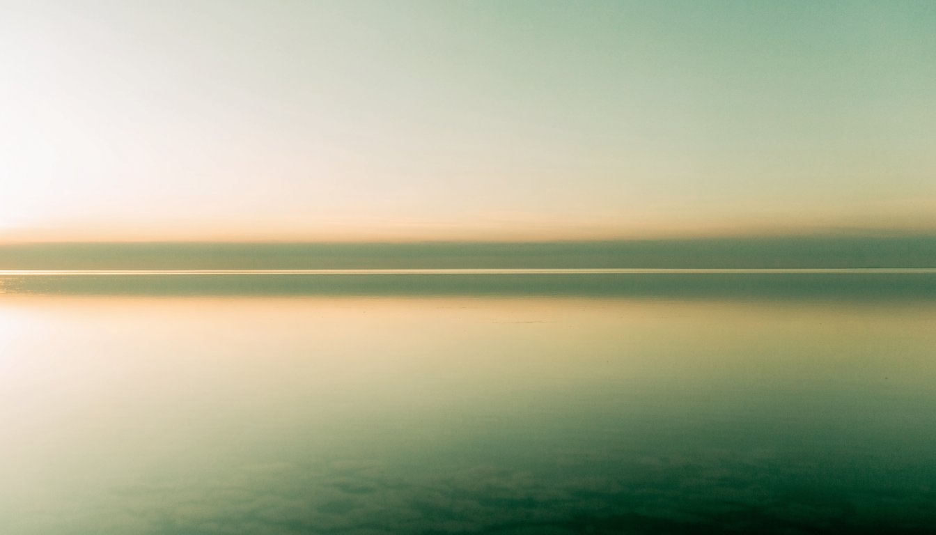 Ein völlig stiller See spiegelt den Morgenhimmel, der Horizont verschwindet fast