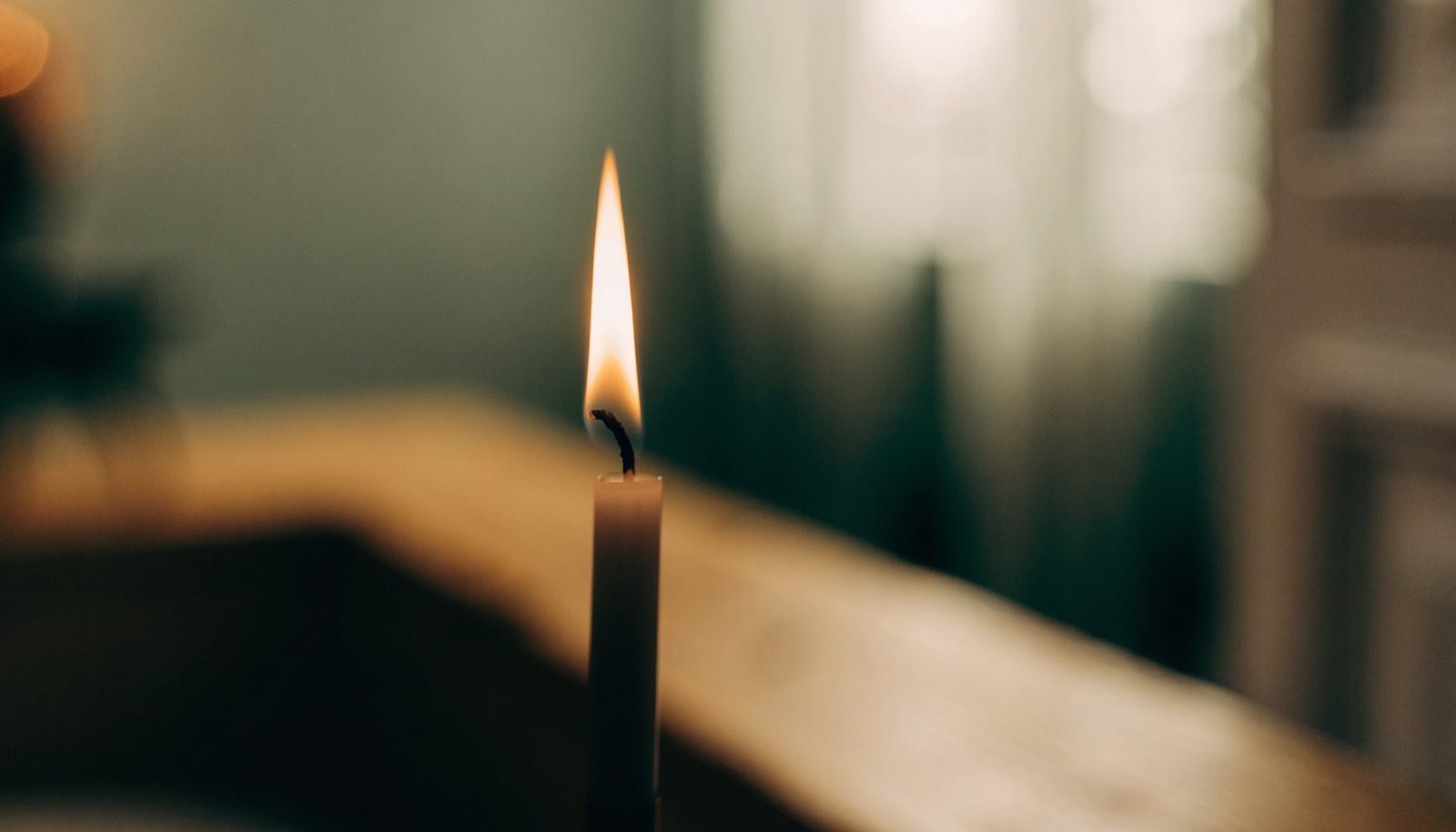 A candle flame burns perfectly still in a quiet room