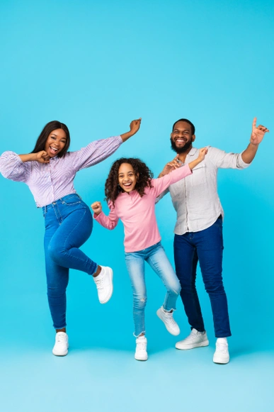 A family of three dancing in joy in a blue background