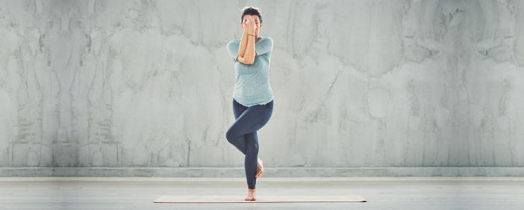 Flexible woman in mahamudra yoga pose indoors. Female yogi sitting in the  great gesture asana over purple wall. Advance practitioner stretching with  hands to big toe. Healthy lifestyle concept Stock Photo