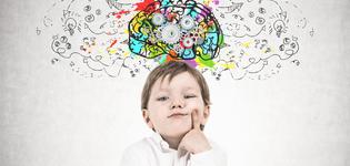 Cute little boy in a white shirt and dark blue jeans is thinking holding his finger near his cheek. Decision making concept. A concrete wall background with a cog brain sketch on it.