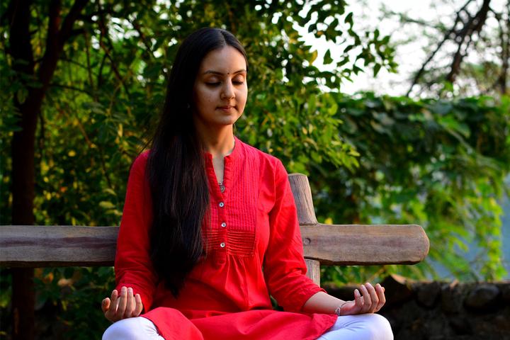 A young woman meditating on a bench in the woods