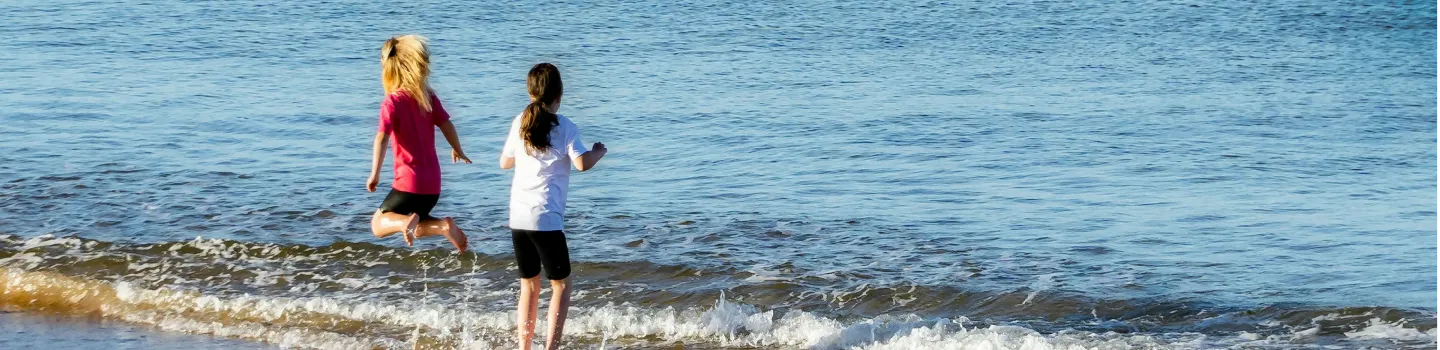 Due bambini che giocano in riva al mare, sguazzando tra le onde, mostrando le abilità di vita di ART Excel