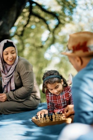 A family of three enjoying their family time in outdoors by playing chess