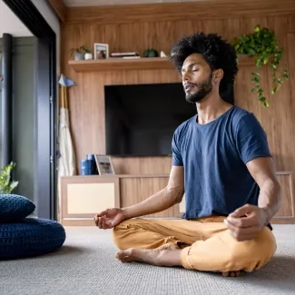 A man sitting with legs crossed in calm room - Meditating