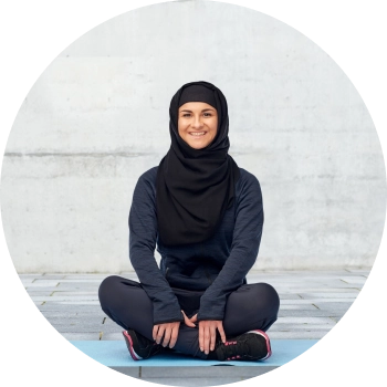 Woman in all black sports hijab sitting with crossed legs and smiling