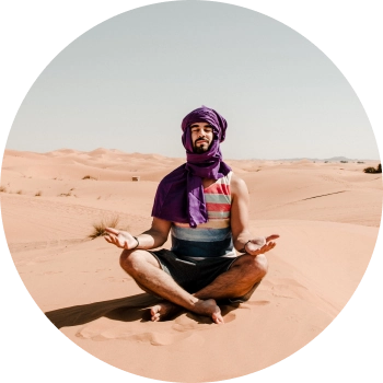 A man wearing Keffiyeh meditating in middle of a dessert