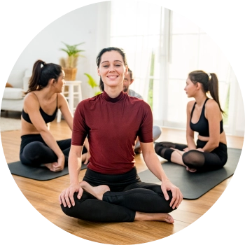 A group of woman sitting cross-legged in a yoga studio, chatting with each other after a yoga session