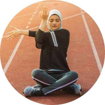 A woman sitting on a running track and stretching  her hands