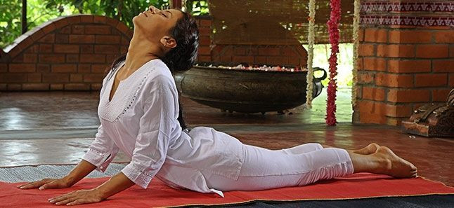 A woman lying on their stomach to practice Bhujangasana as part of yoga poses for weight loss.