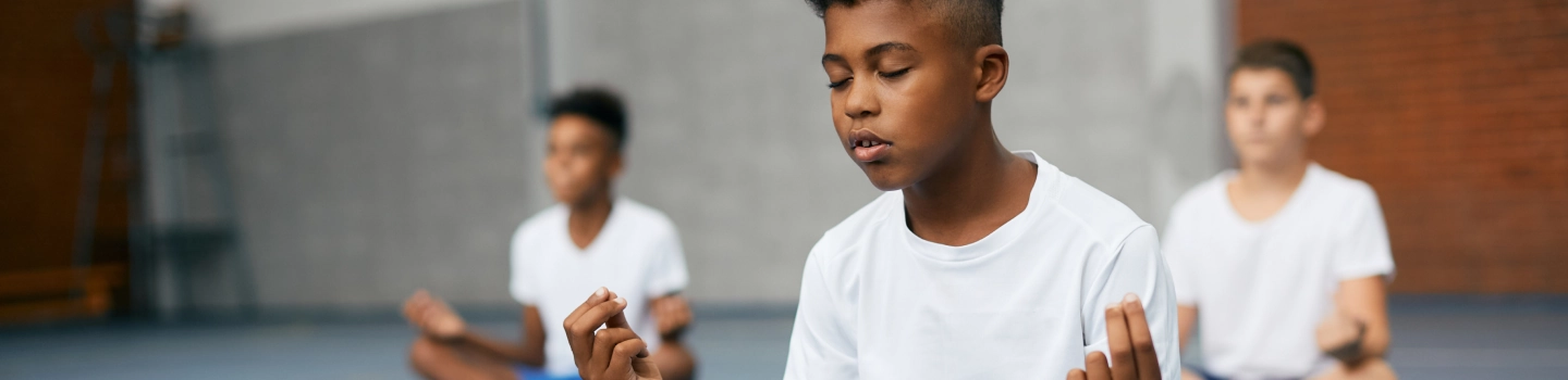 Group of teenage boys meditating with yoga mudra in a yoga studio