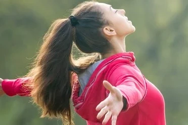 Inner Calm for Youth Teenage girl with arms open wide, breathing deeply in nature, reflecting emotional release, inner strength, and mindfulness