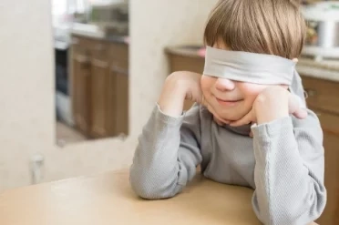 Awakening Inner Senses A smiling boy with a blindfold on, seated at a table, representing intuition process