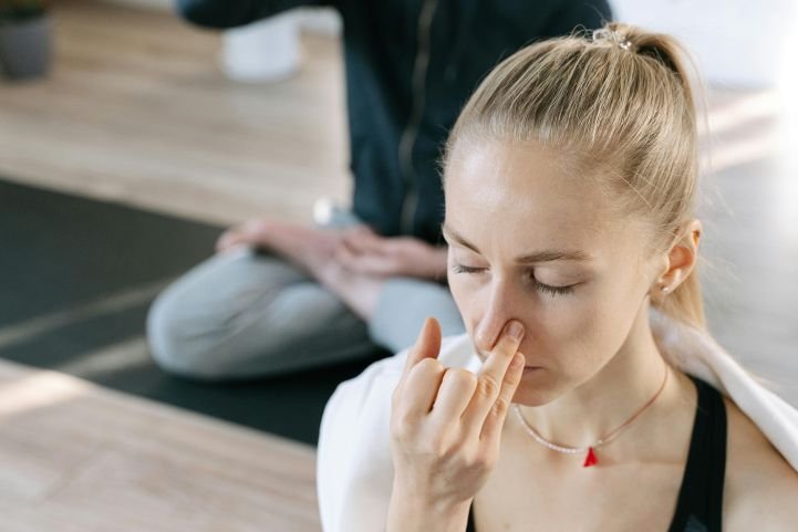 Woman practicing alternate nostril breathing for emotional regulation.