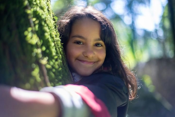 A young girl hugging a tree for stress relief.