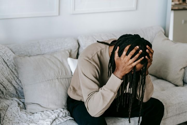 A young man bent over in depression, holding his head.