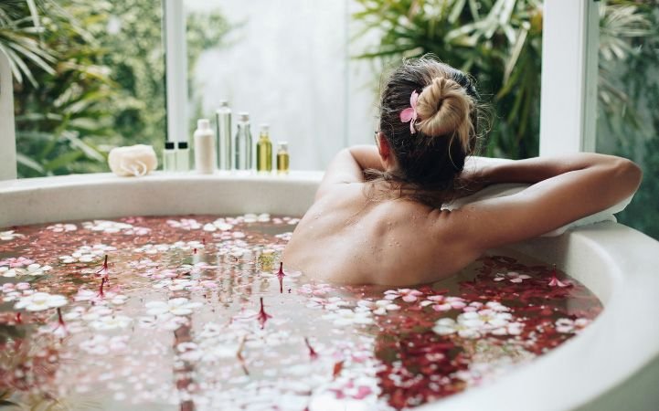 A woman enjoying self-care in the form of a bath with aromatherapy.