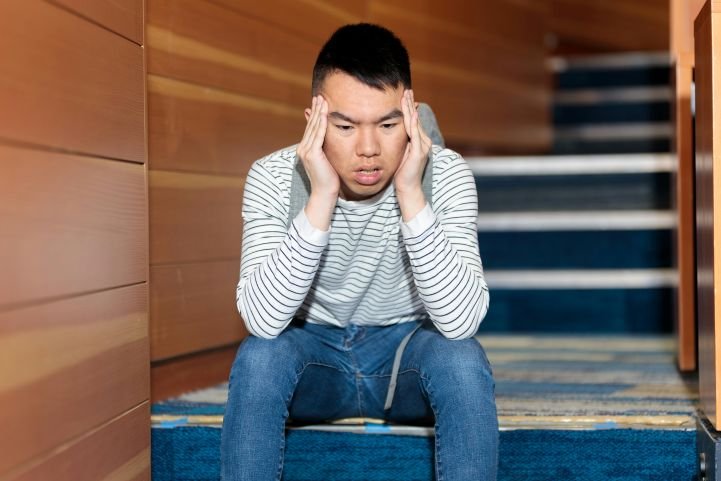 A man is feeling anxiety while sitting on the stairs.