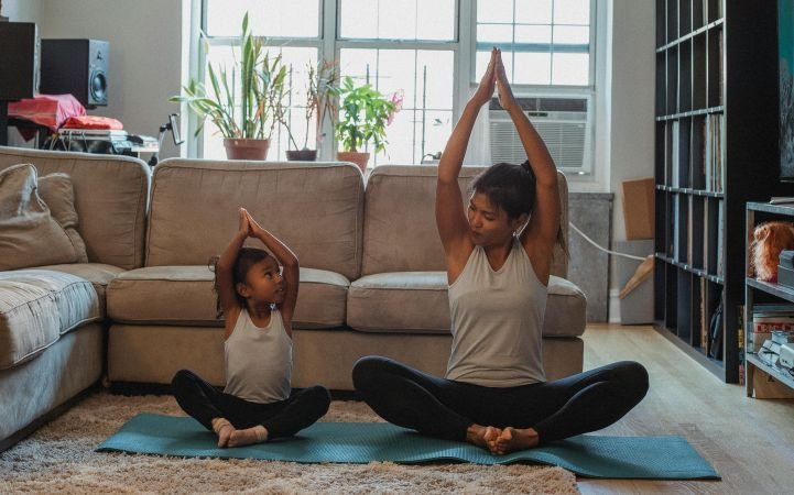 Mother and daughter are doing yoga together as mom practices mindful parenting.