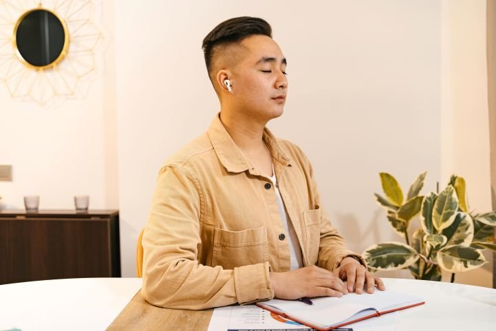 A professional taking a mindful breathing break at a desk to improve focus and reduce stress through meditation.
