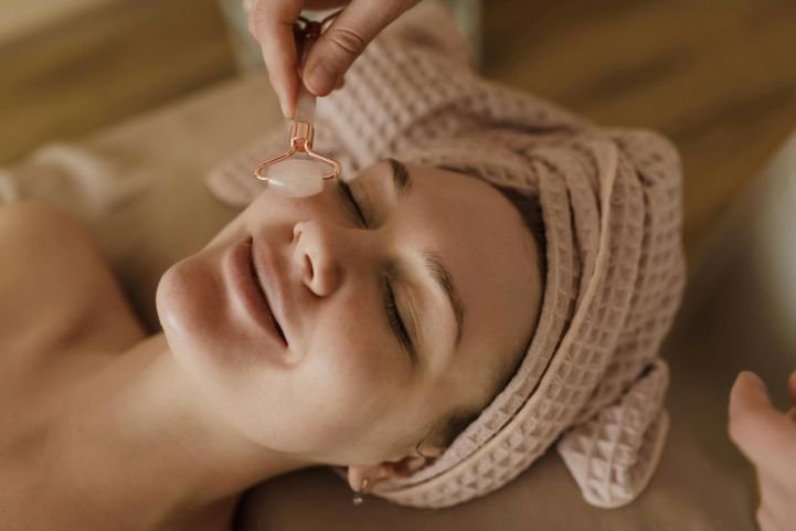 A woman enjoys stress-reduction techniques as a therapist uses a quartz roller on her face.