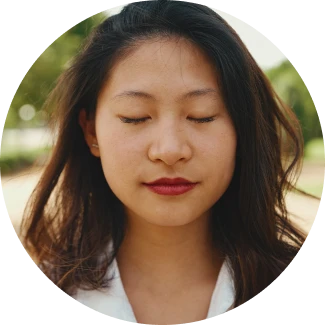 Một người phụ nữ mỉm cười, nhắm mắt đang thiền định.