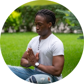 A fit young man sitting with legs crossed in a lawn and meditating