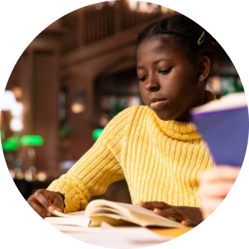 Child girl in yellow shirt writing on paper at a desk