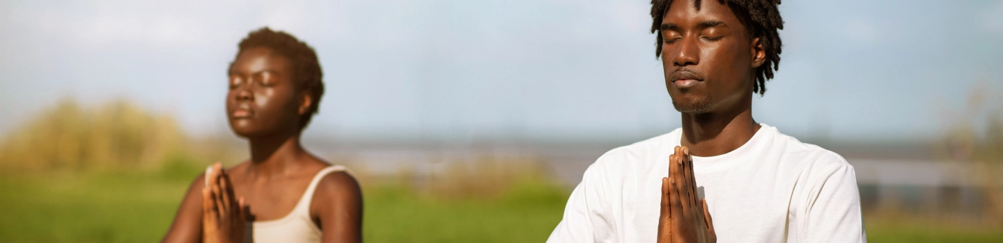 Two people in seated for meditation with hands in prayer position