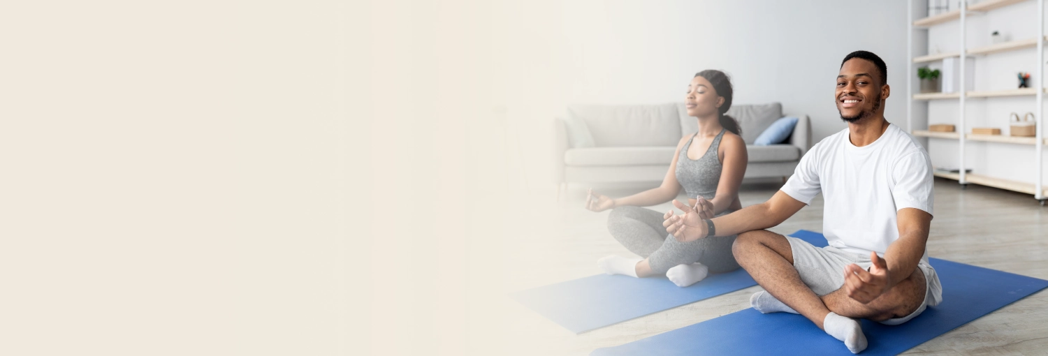 A man and woman meditating in a bright living room